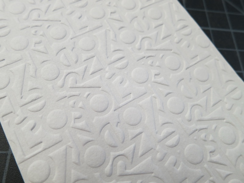 All-over embossed alphabet pattern on white stock