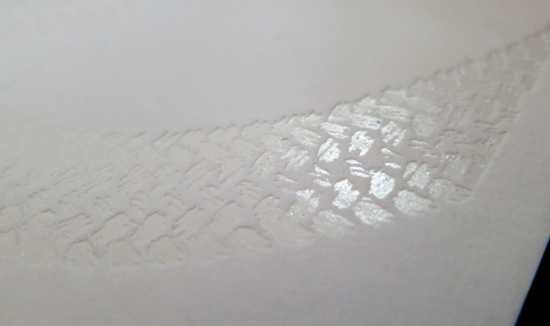 Clear foil snakeskin pattern catching light on white card