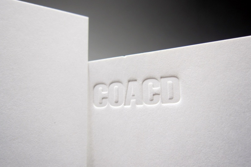 COACD white card with blind-debossed wordmark