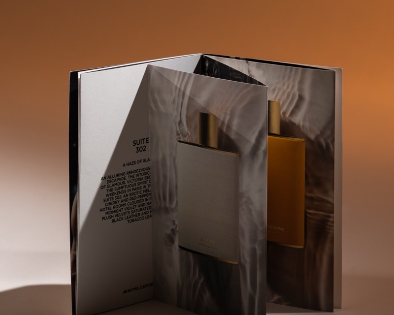 Die-cut fragrance brochure folding open to a bottle window
