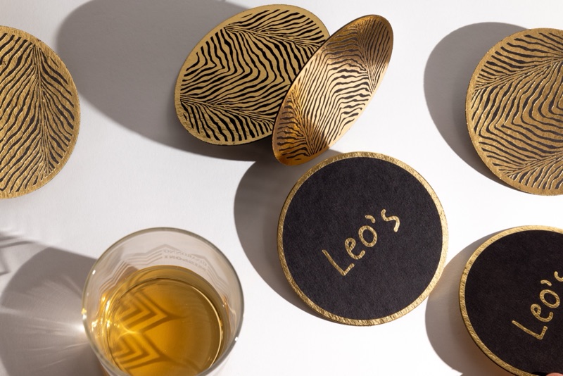 Leo's black and gold embossed coasters styled with a pour of whiskey
