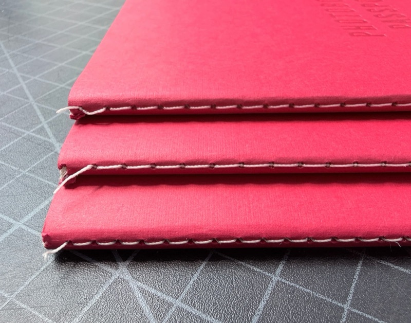 Red singer sewn books with white stitch line